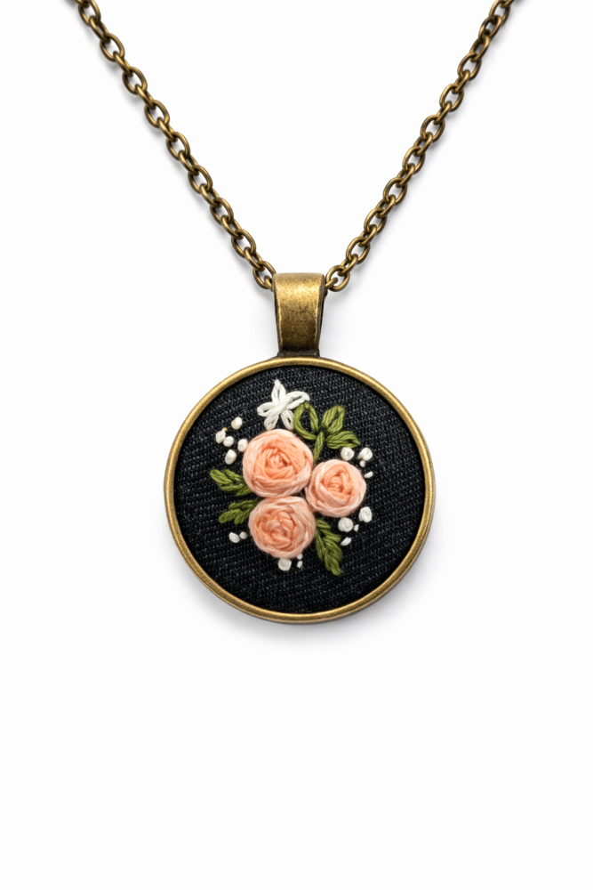 Apaļš kulons ar izšūtām rozītēm ķēdītē