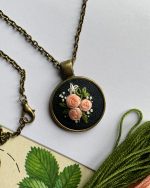 Apaļš kulons ar izšūtiem ziediņiem ķēdītē