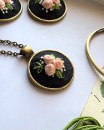 Apaļš kulons ar izšūtām rozītēm ķēdītē