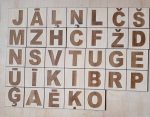 Koka magnētiskās burtiņu flīzes ar latviešu alfabēta burtiem, redzami dažādi latviešu valodas specifiskie burti.