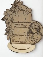 Koka dekors ar gravētu mātes un bērna ilustrāciju, ziedu ornamentiem un personalizētu tekstu “No meitas Agnese”, novietots uz stenda.