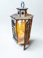 Koka dekoratīvā laterna ar izgrieztiem zvaigžņu un ziemeļbrieža motīviem, ar siltu gaismu iekšpusē.