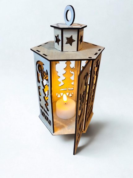 Koka dekoratīvā laterna ar izgrieztiem zvaigžņu un ziemeļbrieža motīviem, ar siltu gaismu iekšpusē.