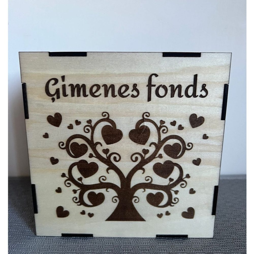 Koka krājkase ar uzrakstu "Ģimenes fonds" un gravētu koka siluetu ar sirds motīviem.
