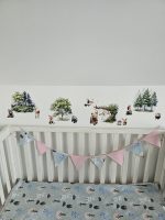 Meža dzīvnieku līmpapīra sienas uzlīmes bērnu istabā – lapsa, lācis, stirna, putni un koki izvietoti bērnu gultiņas garumā uz gaišas sienas.