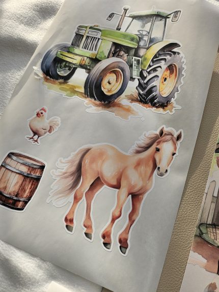 Fermas dzīvnieku līmpapīra sienas uzlīmes bērnu istabā ar govi, jēru, kazlēnu, cāli, kaķēnu un fermas ēkām, izvietotas virs bērnu gultiņas.