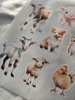 Fermas dzīvnieku līmpapīra sienas uzlīmes bērnu istabā ar govi, jēru, kazlēnu, cālīti, kaķēnu un fermas ēkām, izvietotas virs bērnu gultiņas.