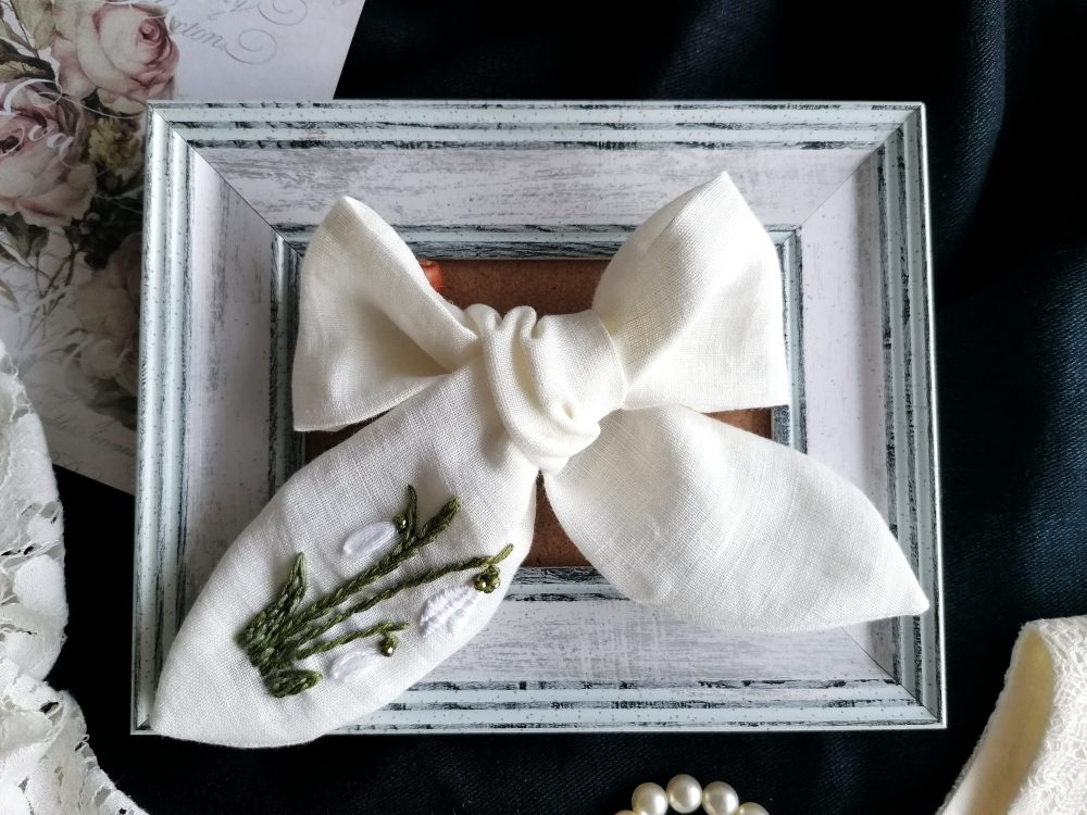 Balta lina matu bante meitenei ar pavasara ziedu izšuvumu, elegants bērnu matu aksesuārs fotosesijām un svētkiem.