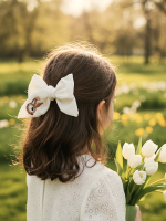 Balta lina matu bante ar zaķīša izšuvumu meitenes matos pavasara fotosesijā.