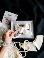 Lina matu bante ar sniegpulkstenīšu izšuvumu uz dekoratīva fona ar pērlēm un mežģīnēm.